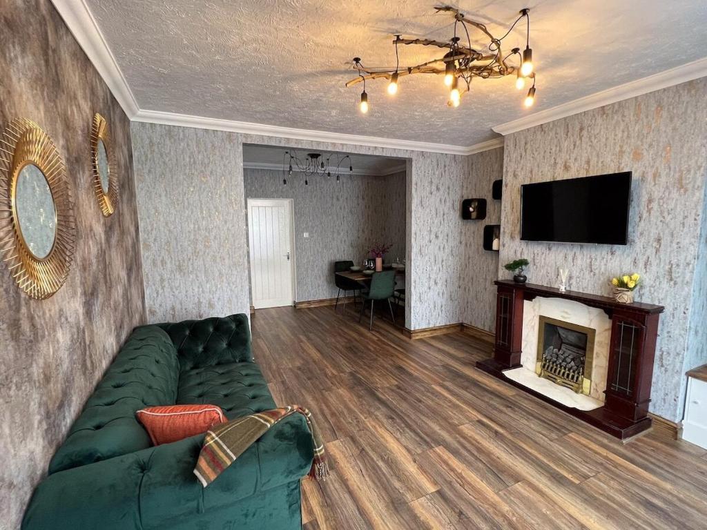 a living room with a green couch and a fireplace at Charming, spacious and cosy home in HULL in Hull