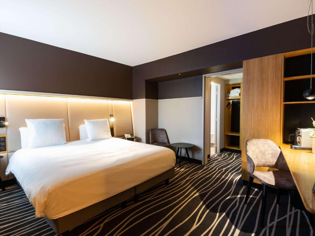 ein Hotelzimmer mit einem großen Bett und einem Schreibtisch in der Unterkunft Mercure Colmar Centre Unterlinden in Colmar