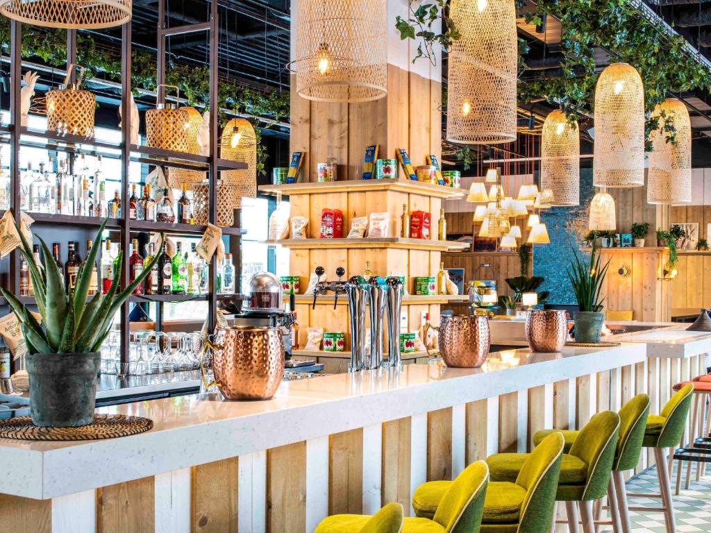 un restaurante con un bar con sillas verdes en Mercure Paris Orly Airport en Orly