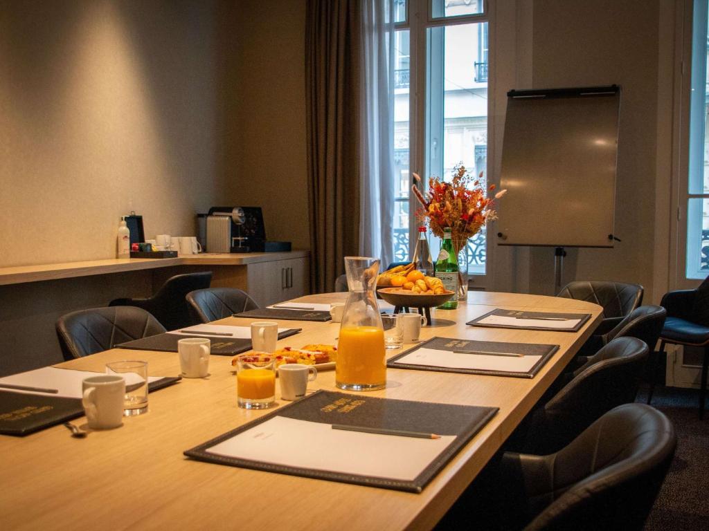 a conference room with a long table with food and orange juice at Mercure Lyon Centre Beaux-Arts in Lyon