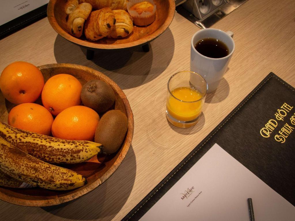 a table with two bowls of fruit and a glass of orange juice at Mercure Lyon Centre Beaux-Arts in Lyon