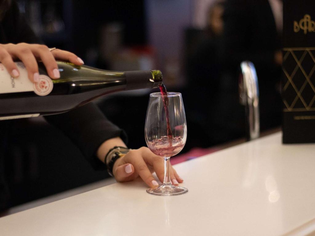 a person pouring a bottle of wine into a wine glass at Mercure Lyon Centre Beaux-Arts in Lyon