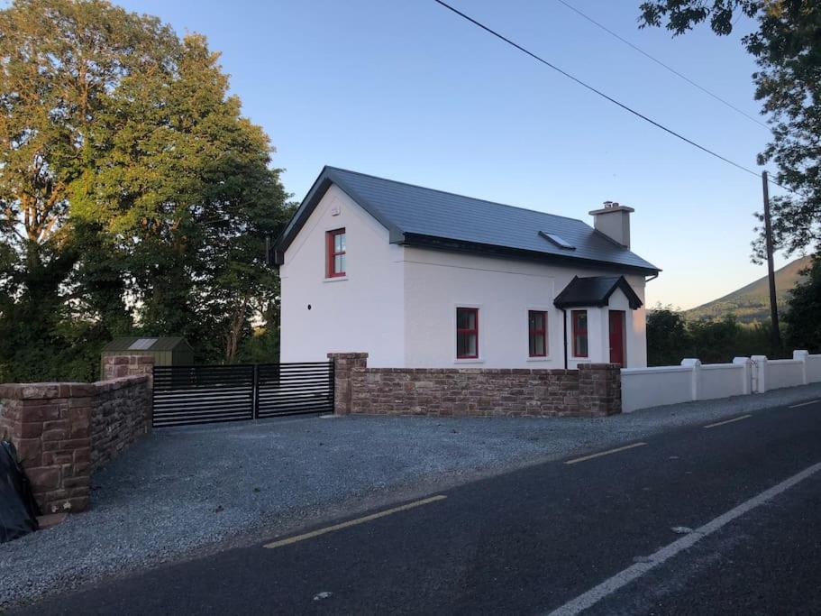 una casa blanca al lado de una carretera en Sunville Cottage, en Limerick