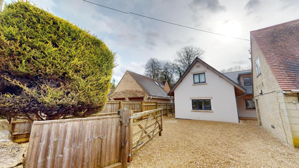 a home with a wooden fence and a house at Pitts Cottage Annexe in Bladon