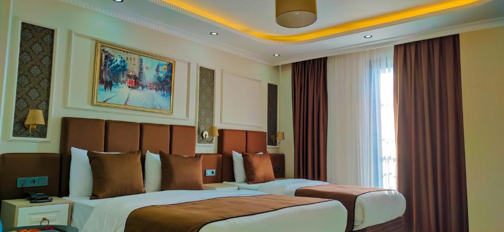 um quarto de hotel com duas camas e uma janela em FRT AİRPORT OTEL em Arnavutköy