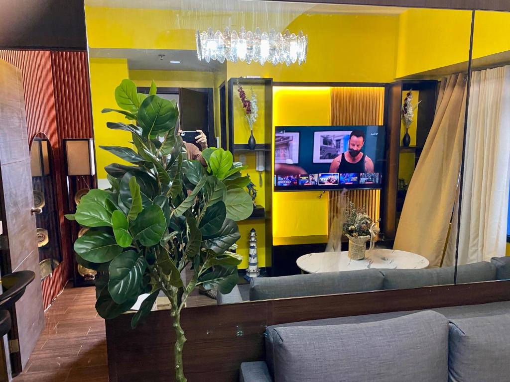 a bathroom with a yellow wall with a mirror and a tv at Laugh and Lounge 2 Bedroom Luxury Condo Air residence Makati in Manila