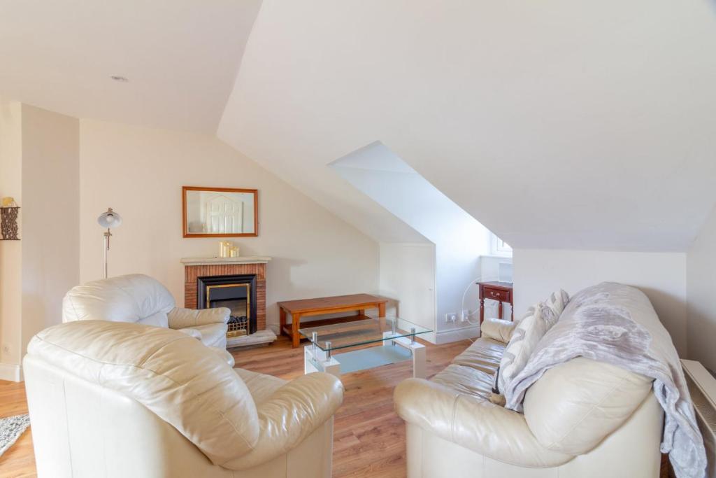 uma sala de estar com duas cadeiras brancas e uma lareira em GuestReady - Castle Proximity and Modern Charm em Dublin