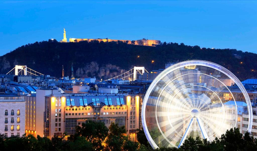 una ruota panoramica di fronte a una città di notte di Kempinski Hotel Corvinus Budapest a Budapest