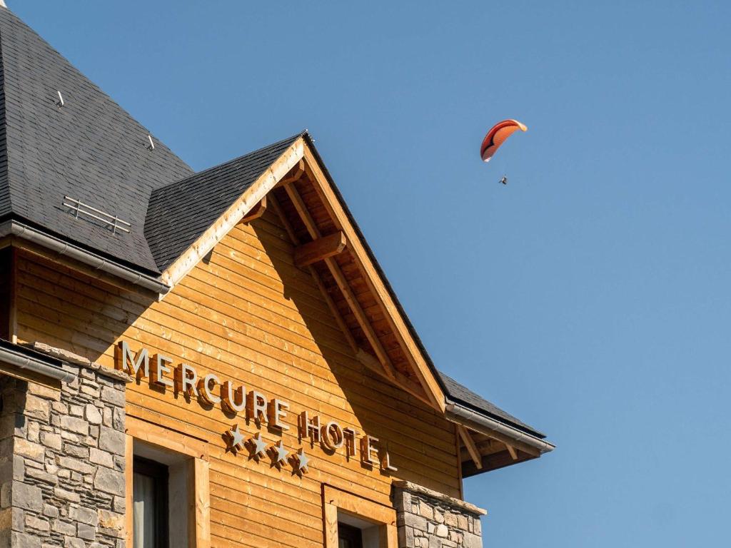 una cometa volando sobre un edificio con un cartel en él en Mercure Peyragudes Loudenvielle Pyrénées, en Loudenvielle