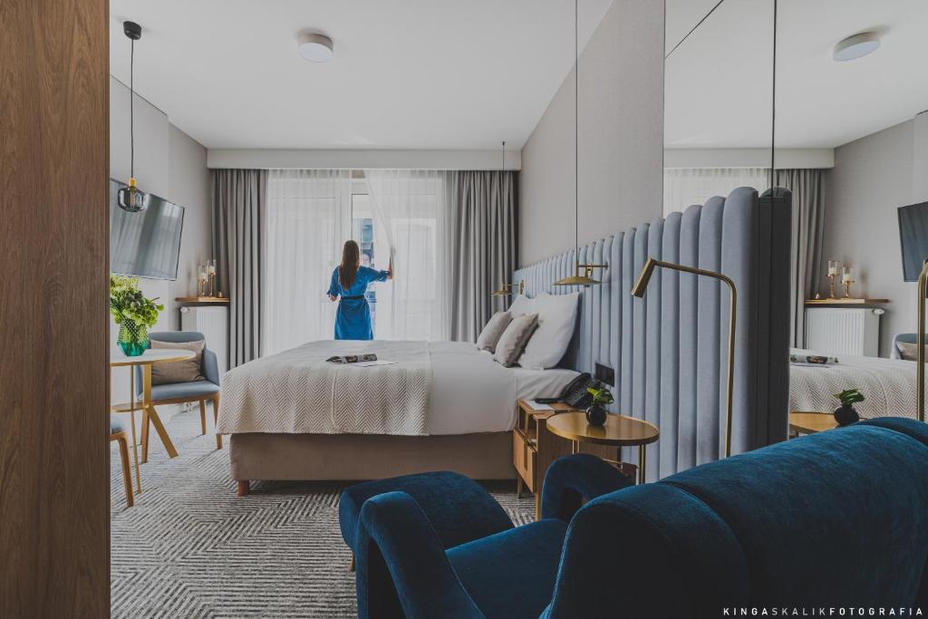 Una mujer está de pie en una habitación de hotel en Royal Tulip Warsaw Apartments en Varsovia
