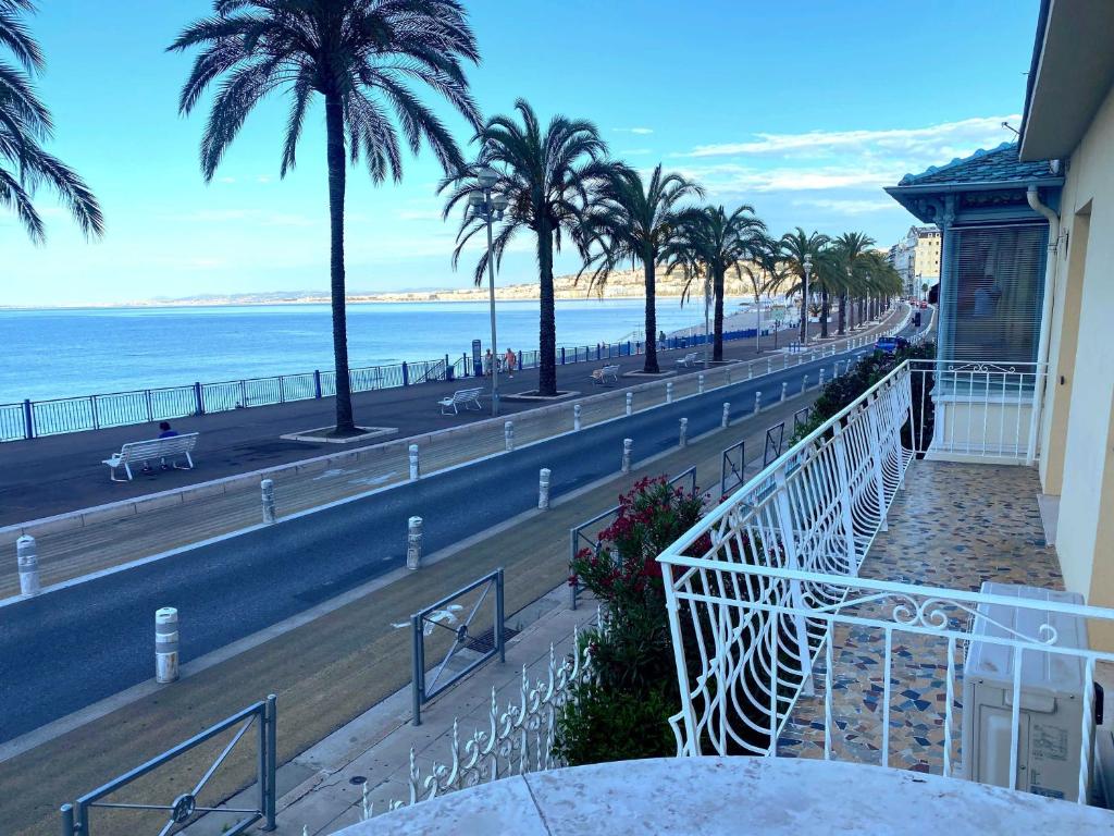un balcon avec vue sur la plage et les palmiers dans l'établissement Villa kriss, à Nice
