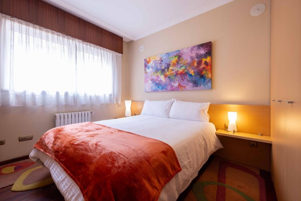 1 dormitorio con 1 cama y una pintura en la pared en Apartamento SpítiCasa, en Santiago de Compostela