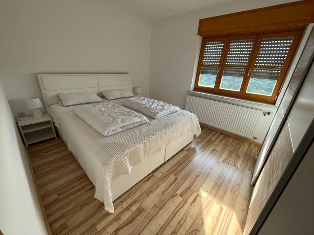 a bedroom with a white bed and a window at Raus aufs Land in Ederberg