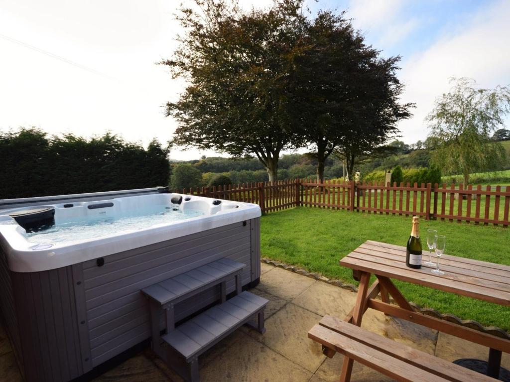 a hot tub with a picnic table and a bottle of wine at 2 Bed in South Molton 62654 in Filleigh