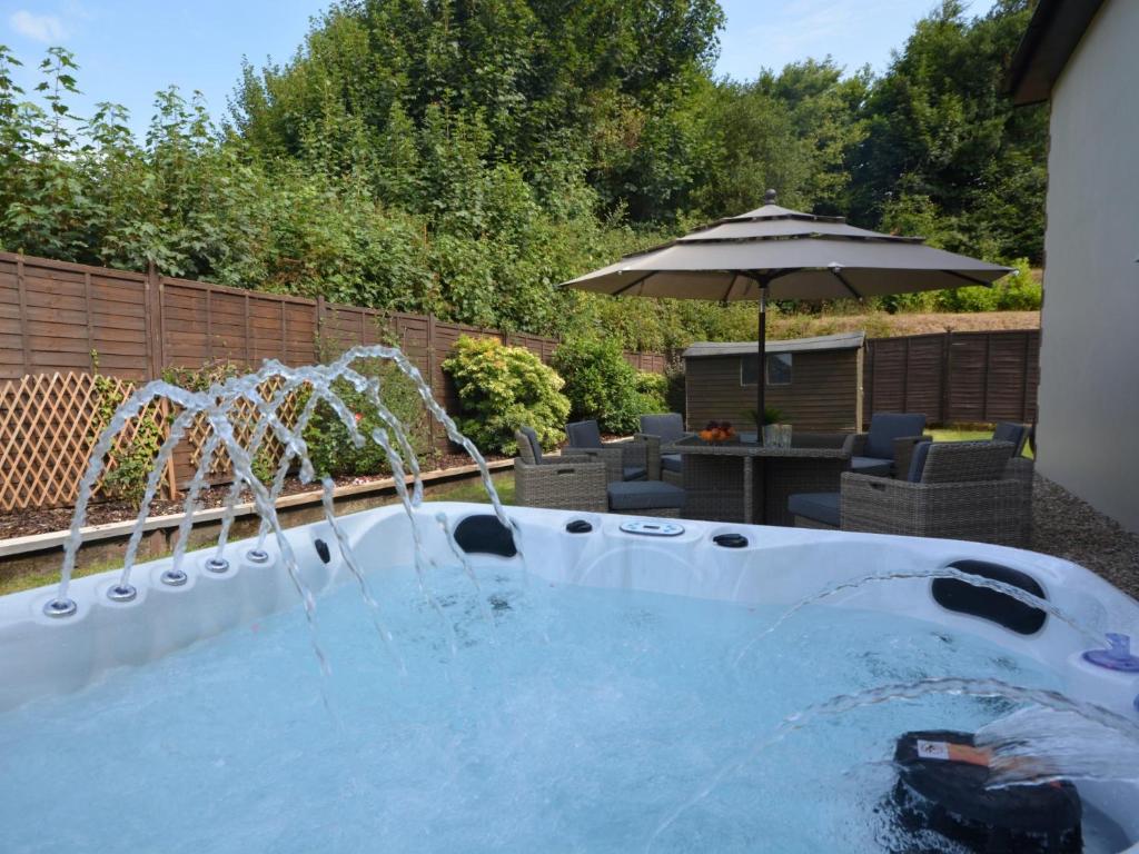 - une piscine d'eau avec un parasol dans la cour dans l'établissement 3 Bed in South Molton 62655, à Filleigh