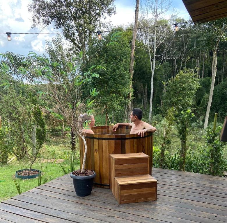 un hombre en una bañera en una cubierta en Cabana com Ofurô e Cinema a 6km do Centro, en Ibicaré