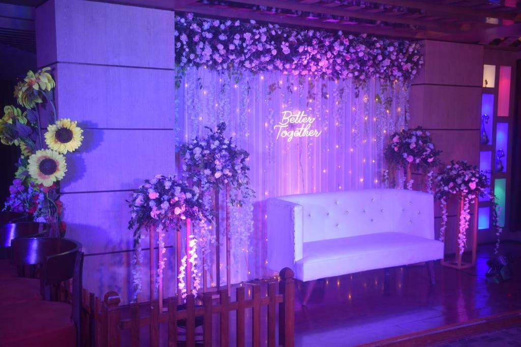 a purple stage with a white couch and flowers at HOTEL SHOOLIN GRAND in Guwahati