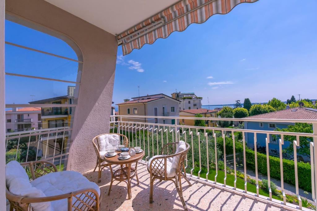 een balkon met stoelen en een tafel met uitzicht bij Appartamento La Maison Fleurie - Happy Rentals in Desenzano del Garda