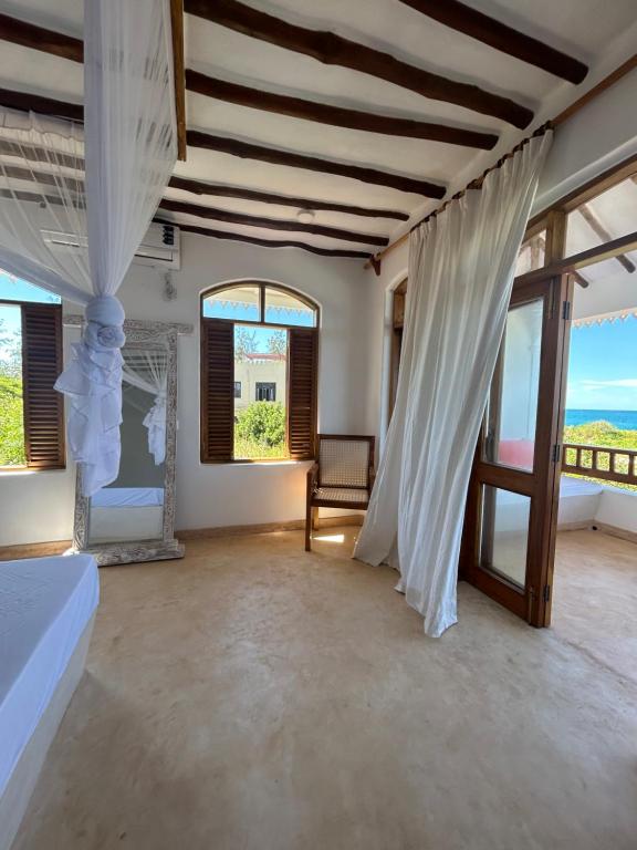 a bedroom with a bed and a room with windows at Sea view house in Kilifi