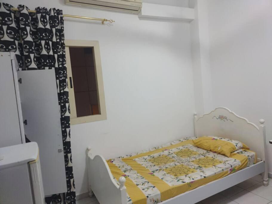 a small bedroom with a bed in a white room at Furnished Studio for Rent in Sharjah