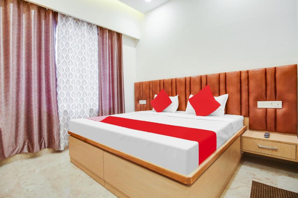 a bedroom with a large bed with red pillows at OYO Flagship Dhruva Residency in Shāhpur