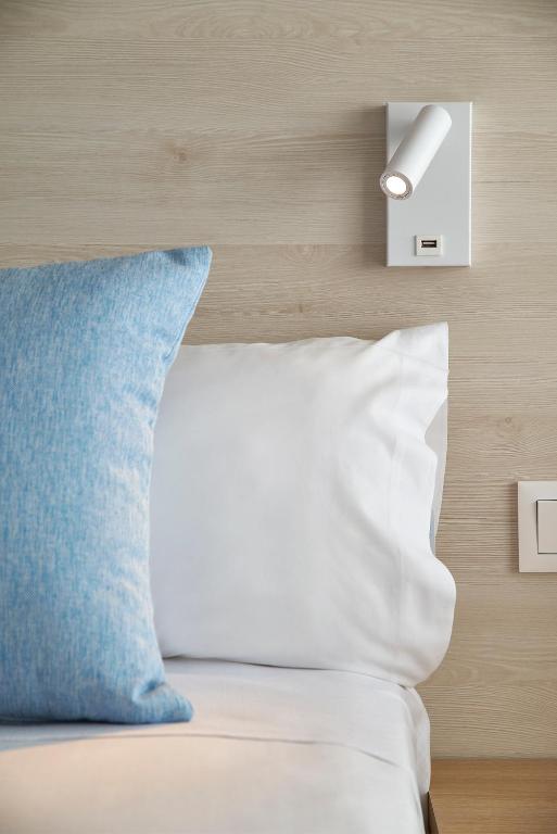 a bed with a blue pillow and a light switch at URH Excelsior in Lloret de Mar