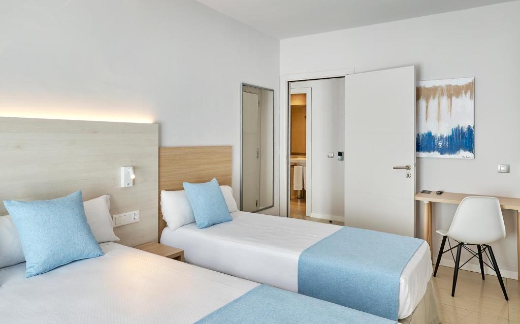 a hotel room with two beds and a desk at URH Excelsior in Lloret de Mar