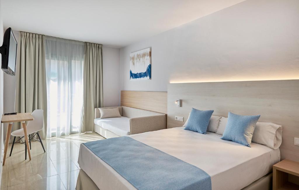 a hotel room with a large bed and a chair at URH Excelsior in Lloret de Mar