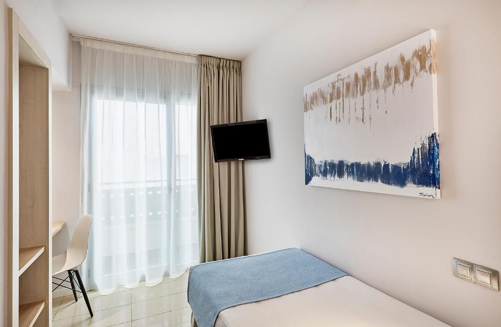 a white room with a bed and a window at URH Excelsior in Lloret de Mar