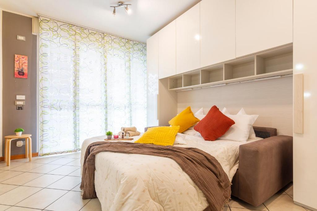 ein Schlafzimmer mit einem Bett mit bunten Kissen darauf in der Unterkunft Casa Carlyta - Vicino Ospedale San Raffaele e Metro M2 in Vimodrone
