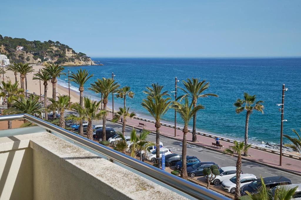 a view of a beach and palm trees and the ocean at URH Excelsior in Lloret de Mar