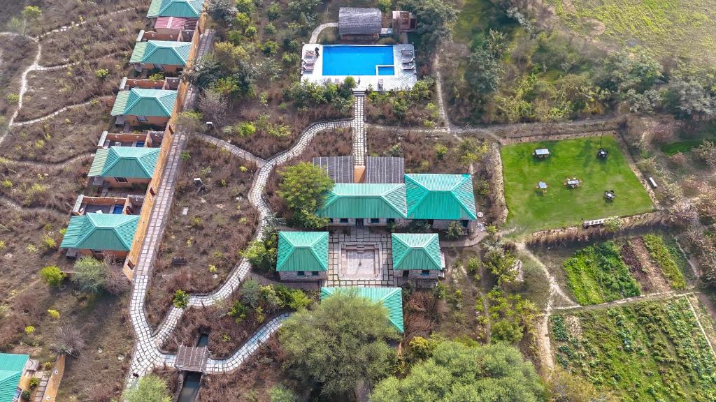 Bagh Serai - Rustic Cottage with Private Pool في ساواي مادهوبور: اطلالة جوية على منتجع مع ملعب
