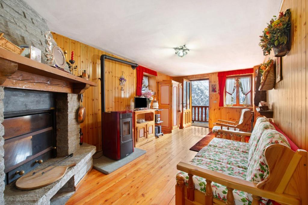 a living room with a fireplace and wooden walls at Casa Betulla Champorcher in Champorcher