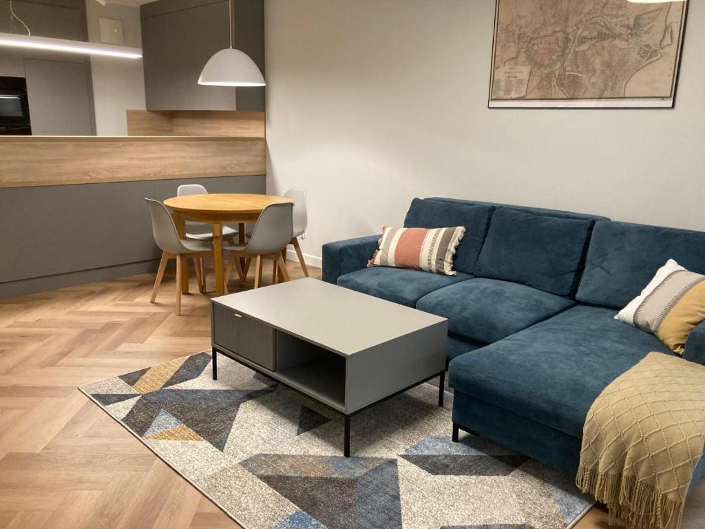 a living room with a blue couch and a table at Wilcza City Center Apartments in Gdańsk