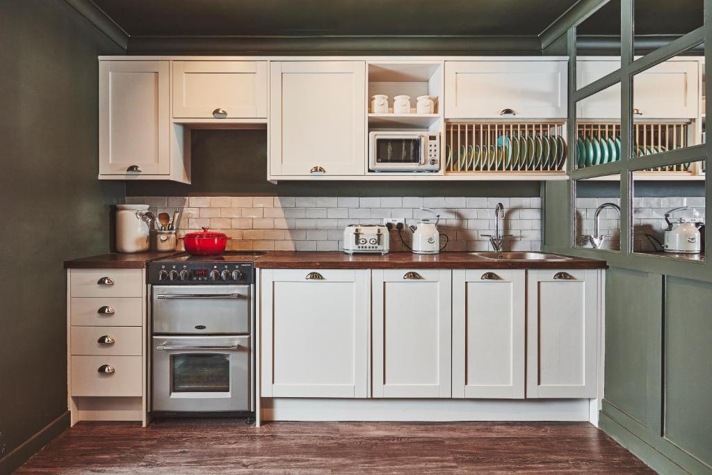 a kitchen with white cabinets and white appliances at No.26 By The Sea in Oban