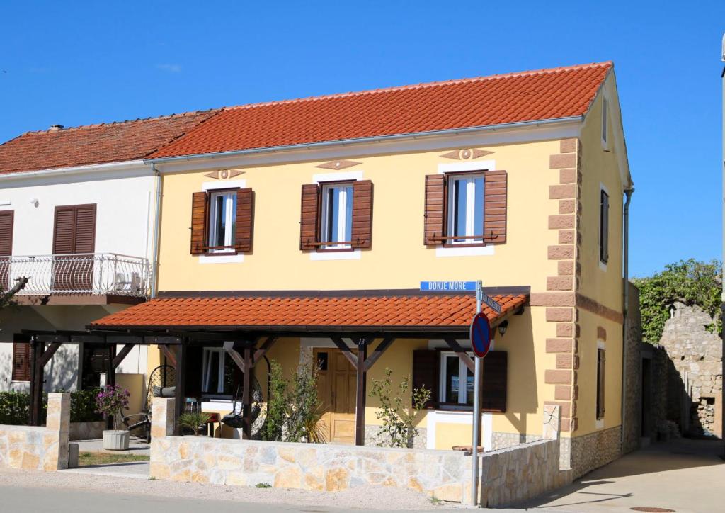 een geel gebouw met een rood dak bij Villa Galleria in Sukošan