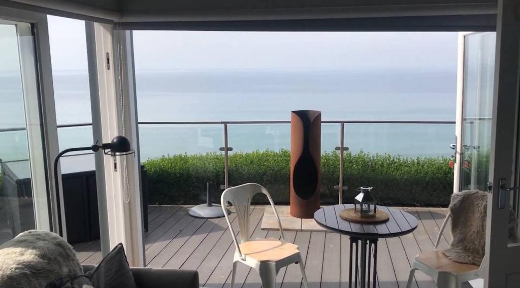 a room with a balcony with a table and chairs at Luxury home on Whitsand Bay in Cawsand