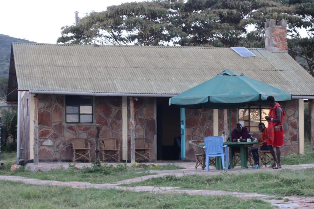 un homme debout devant une maison avec une table dans l'établissement NAUNERI HOMES, à Sekenani