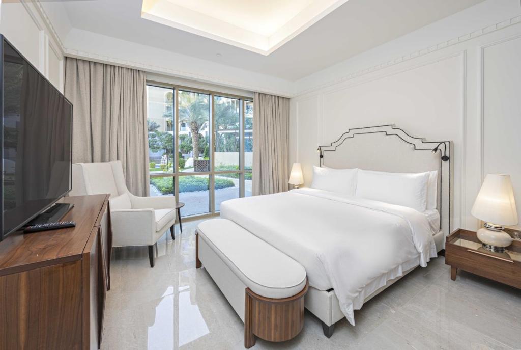 a white bedroom with a large bed and a television at Town house residency 2 in Doha
