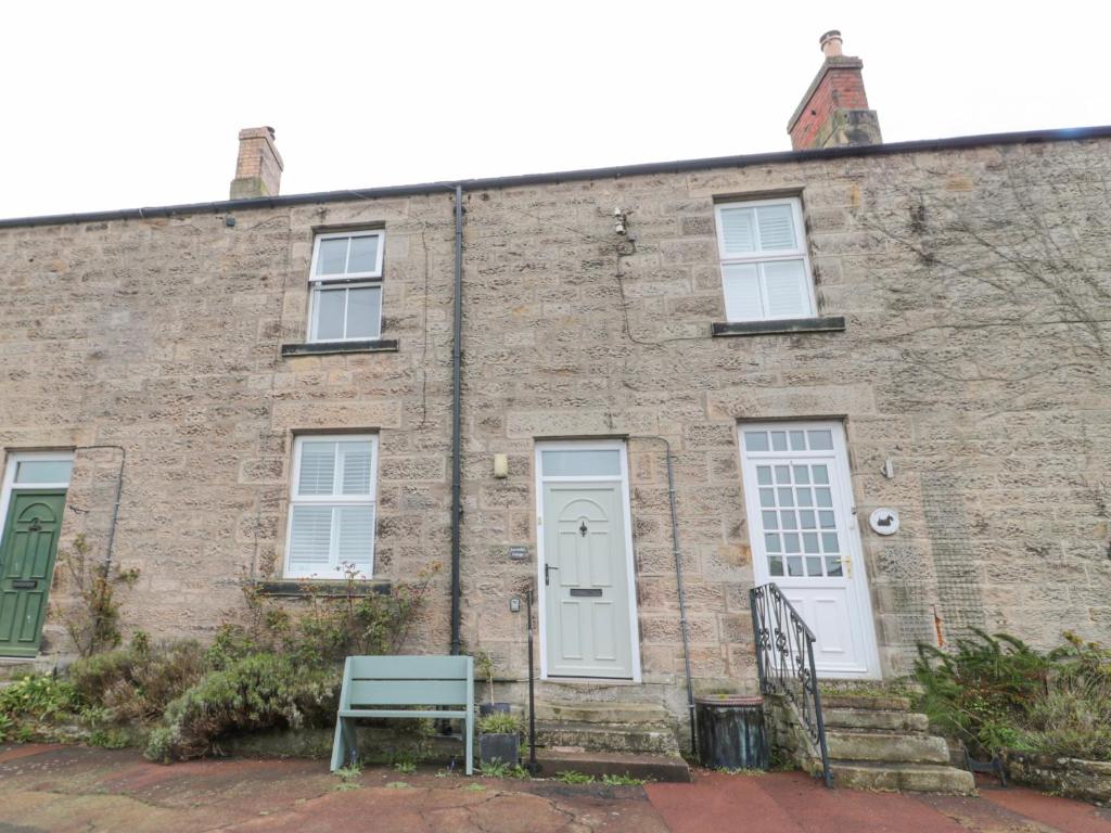 an old brick building with a blue bench in front of it at Lavender Cottage in Alnwick