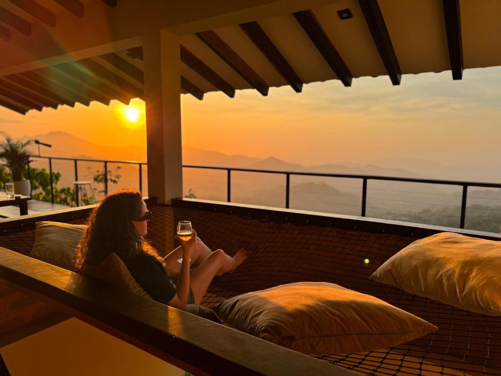 Villa Canopy Minca في مينسا: امرأة تجلس على مقعد مع كوب من النبيذ