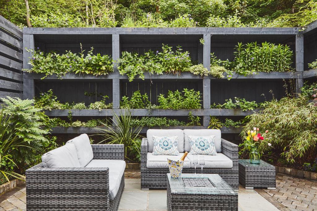 a patio with wicker furniture and a fence with plants at No.26 By The Sea in Oban