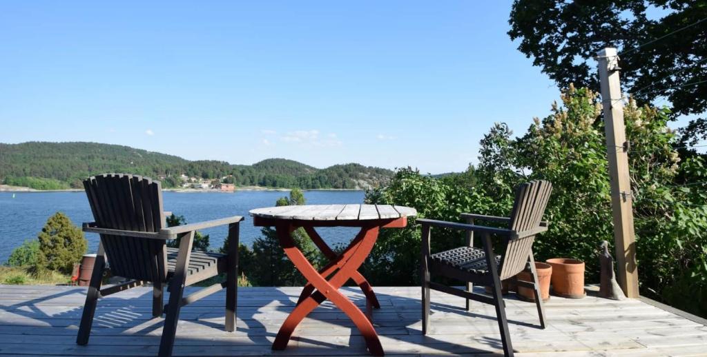 2 Stühle und ein Tisch auf einer Terrasse mit Blick auf das Wasser in der Unterkunft Underbart hus med fantastisk havsutsikt & nära till bad in Svanesund