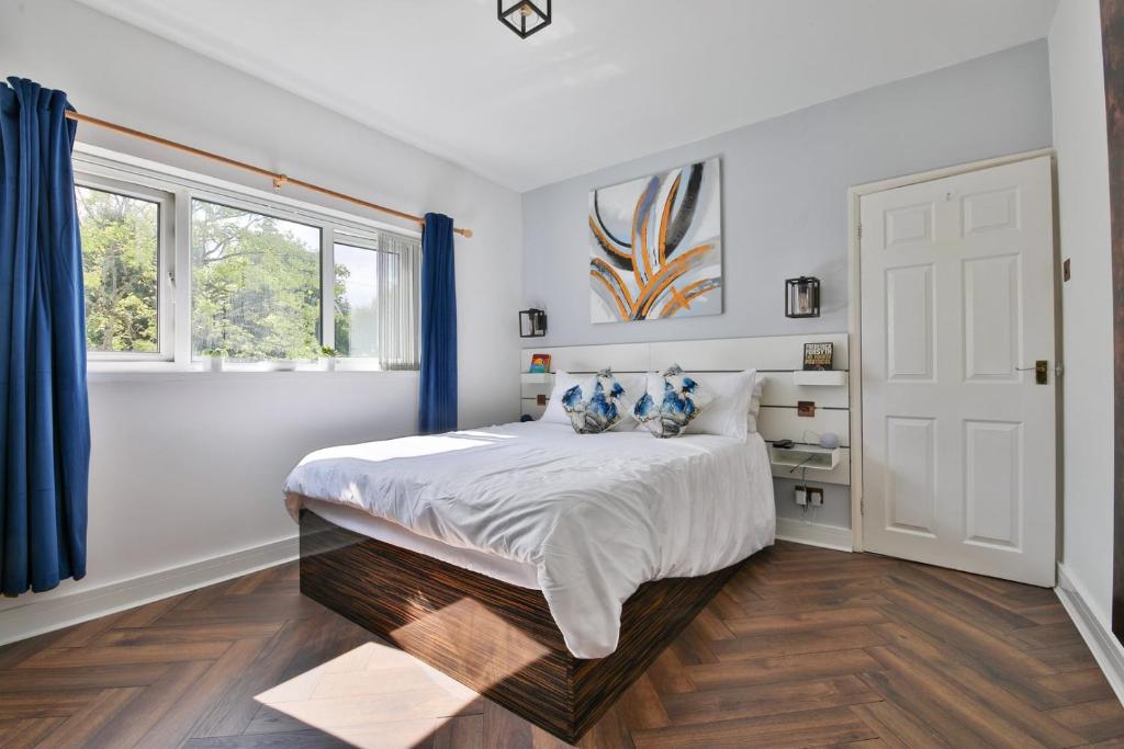 a bedroom with a large bed with blue curtains at Garden Station Dwelling in Rumney in Cardiff