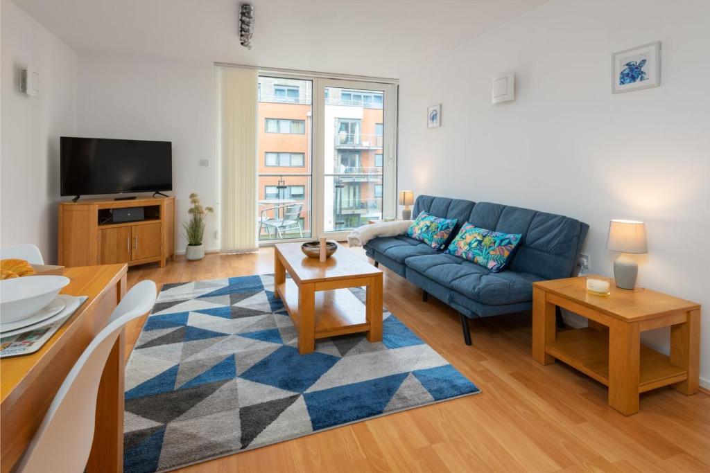 a living room with a blue couch and a tv at The Ocean Village, Southampton in Southampton