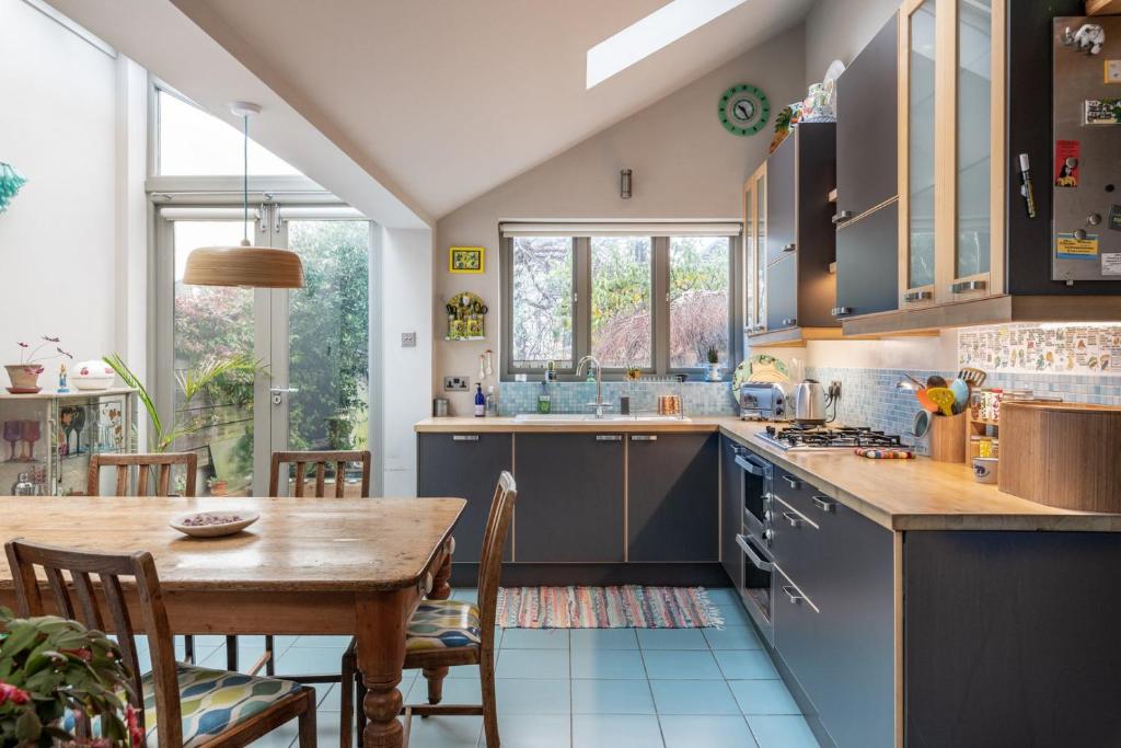 a kitchen with blue cabinets and a wooden table at GuestReady - Magic Lantern House - Close to Beach in Brighton & Hove