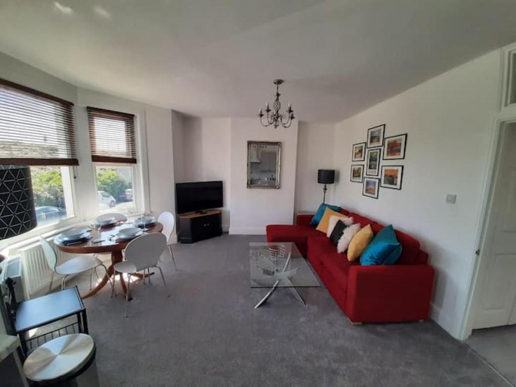 a living room with a red couch and a table at Beautiful 2BR Home close to Beachfront in Weston-super-Mare