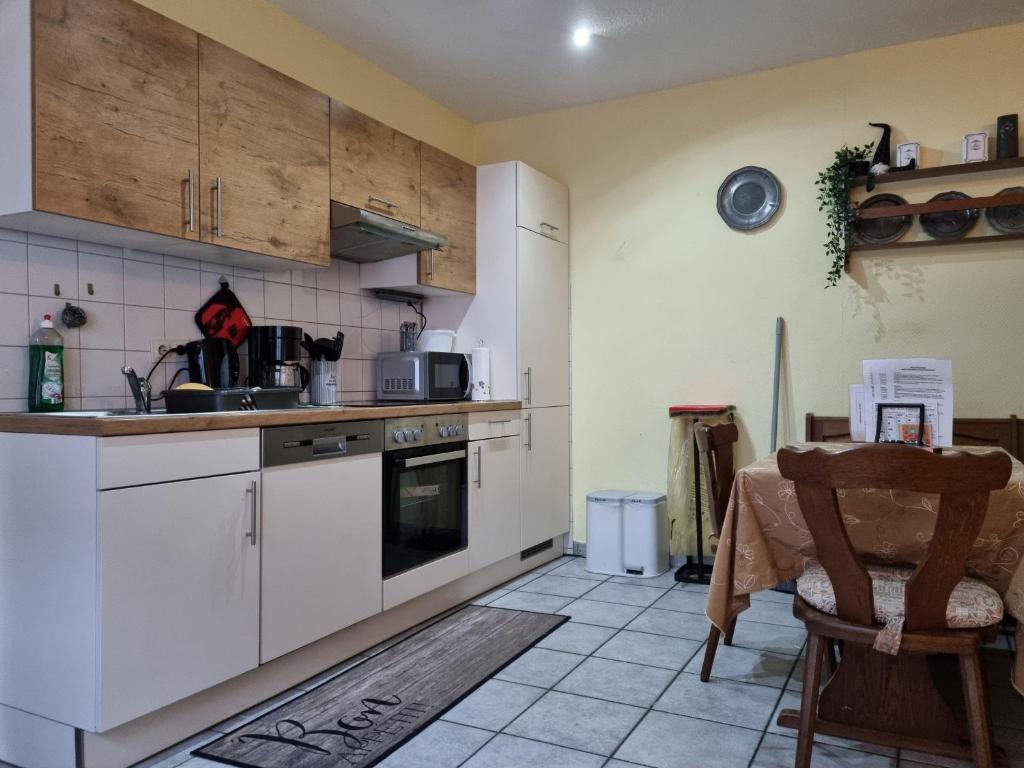 a kitchen with white cabinets and a table in it at App-O1-2-3-Personen-23km-bis-Frankfurt-Nord in Ober-Mörlen