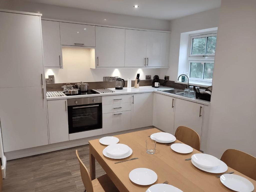 a kitchen with a wooden table and white cabinets at Refúgio de charme no Peak District in Leek