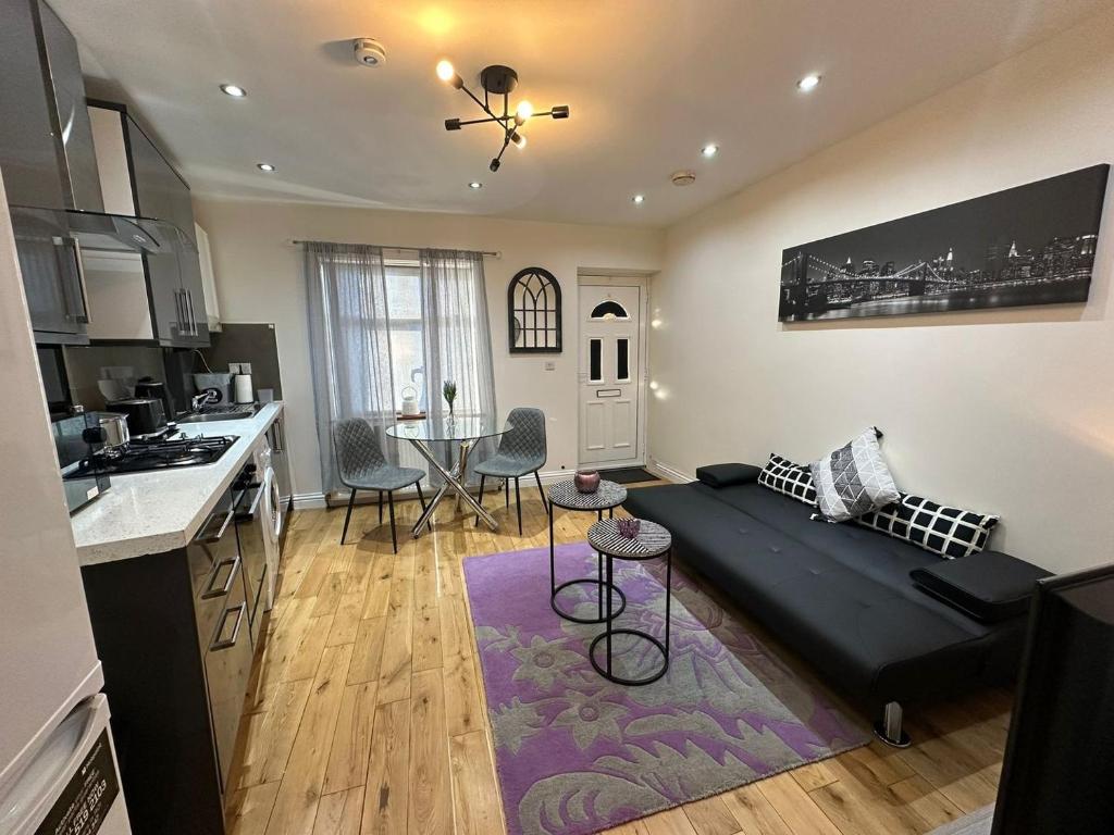 a living room with a black couch in a kitchen at Snug retreat in Reading in Earley